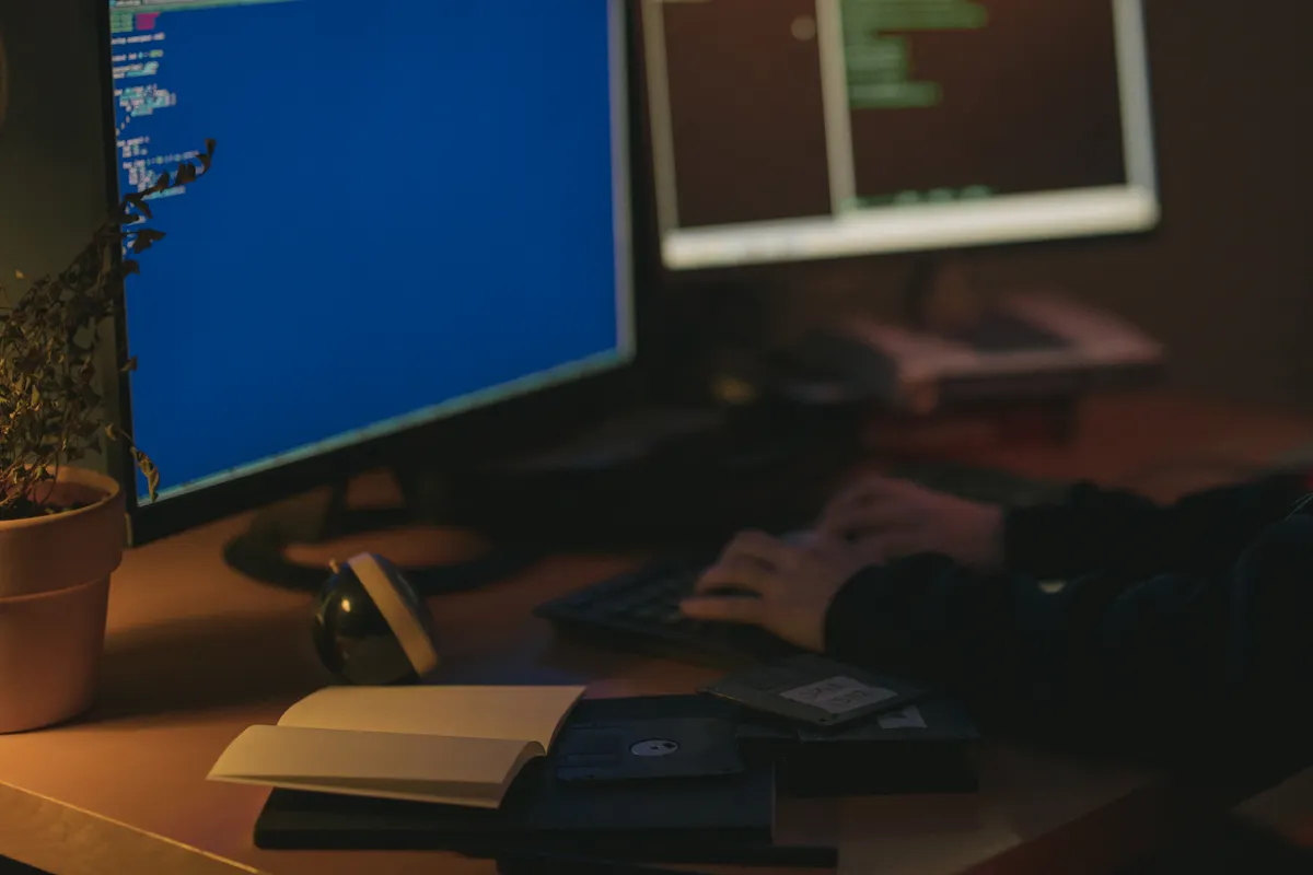 Programador trabajando con dos monitores en penumbra